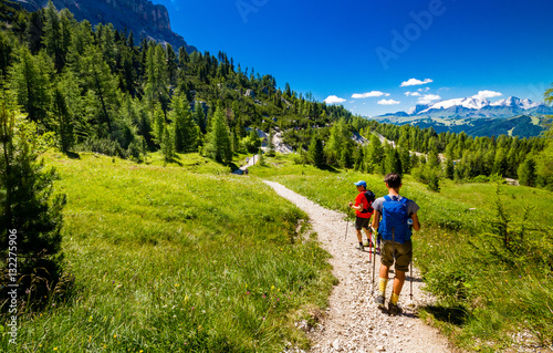 Pair of excursionist walking on mountainous trail. Summer Trekking