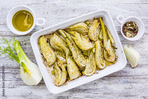 Baked fennel with herbs and olive oil on wooden background.