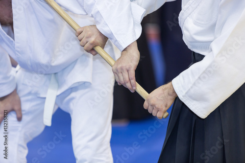 People practice Aikido with wooden jo on martial arts training seminar