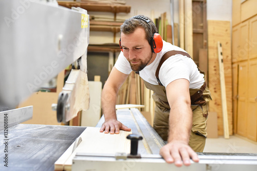 Tischler sägt Holzbrett in einer Schreinerei // Carpenter sawing wooden board in a carpenter's workshop