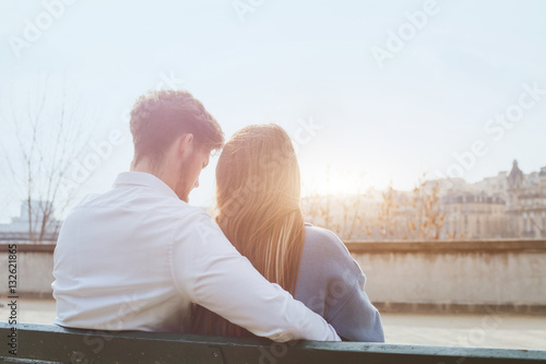 dating or first love, young couple sitting together on the bench, view from the back