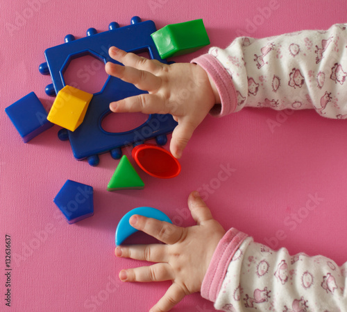 Children playing with montessori toys, educational toys, arranging and sorting colors and sizes isolated on pink.