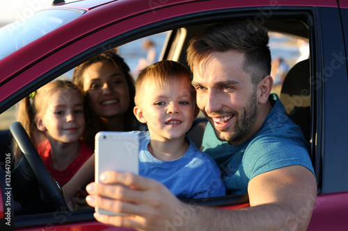 Parents with kids taking photo in car