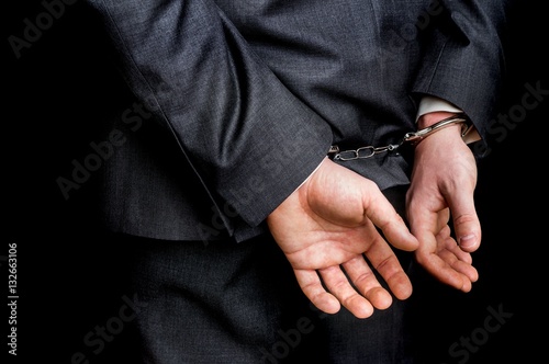 Arrested businessman in handcuffs with hands behind back