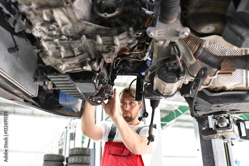 Automechaniker repariert defektes Fahrzeug auf der Hebebühne in einer Werkstatt 