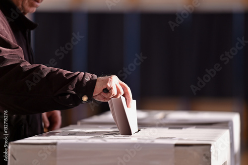 Person casting vote into ballot box