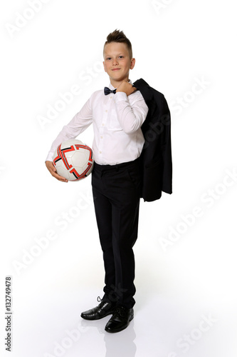 Młody chłopiec w garniturze trzyma piłkę