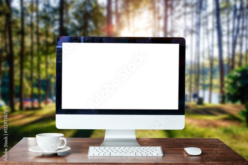 Computer Monitor, Keyboard,coffee cup and Mouse with Blank or White Screen Isolated is on the work table in the dark forest