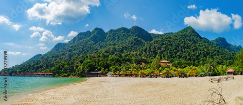 Relaxing on remote paradise beach. Tropical bungalow and luxury house on untouched sandy beach with palms trees in Langkawi Island, Malaysia.