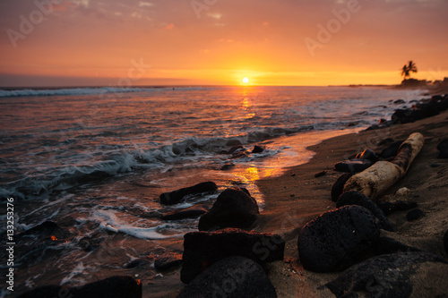 Waves from ocean crashing on rocks on beach at sunset in Hawaii
