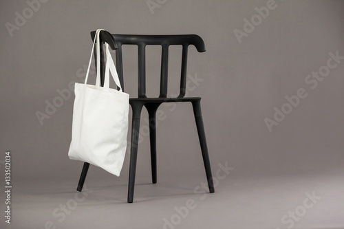 White shopping bag hanging on black chair