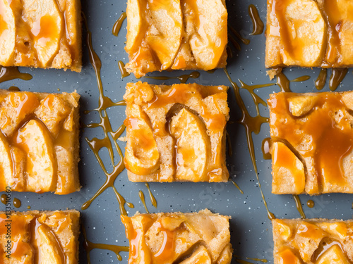 Home made apple cinnamon blondies with salted caramel. Sweet food home made dessert treat. Dark blue background flat lay