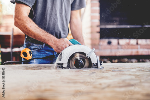 Construction worker, industrial carpenter using circular miter saw for cutting boards