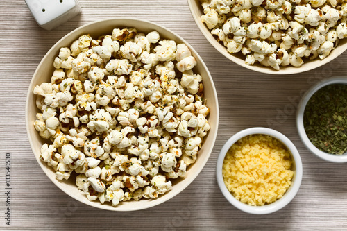 Homemade fresh savory popcorn with cheese, garlic and dried oregano in bowls, photographed overhead with natural light (Selective Focus, Focus on the top of the popcorn)