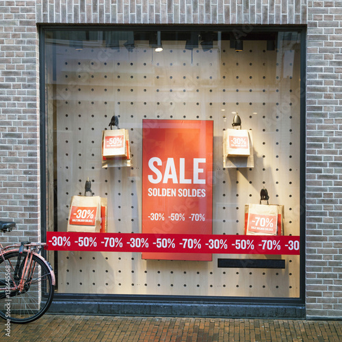 sale signs on paper bags in display window of clothing store