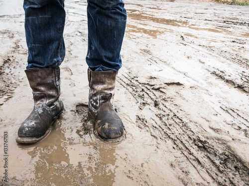 Dirty brown boots on the mud when raining