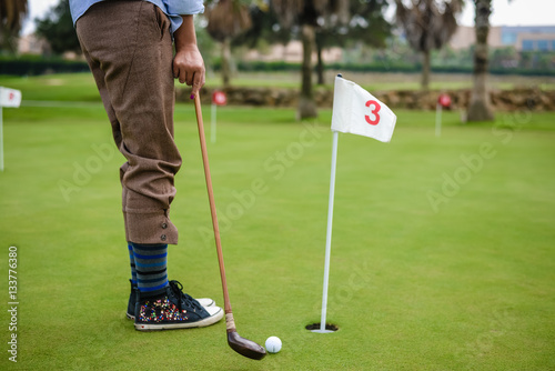 Retro wooden golf club and ball on green field outdoors background