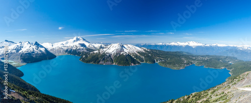 Panoramic wide scenery from Panorama Ridge peak with view over whole Garibaldi lake and surrounding mountains covered in snow during sunny summer day, Whistler, British Columbia, Canada.