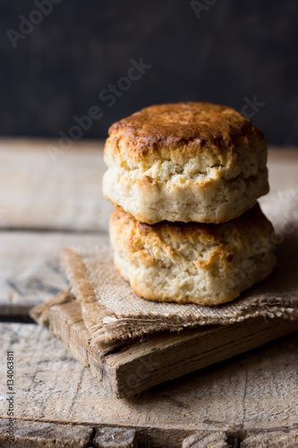 Stack of homemade scones on burlap on vintage wood table, black wall, rustic kitchen interior, minimalistic, kinfolk