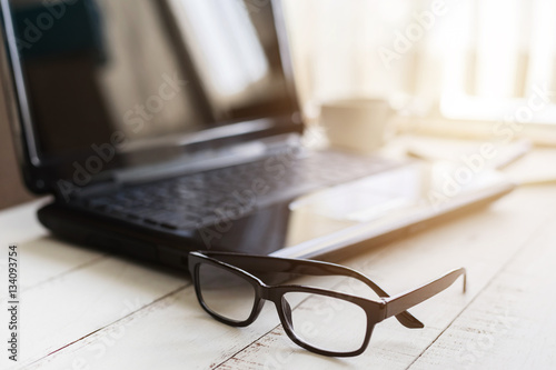 Eyeglasses on office desk with laptop at workplace