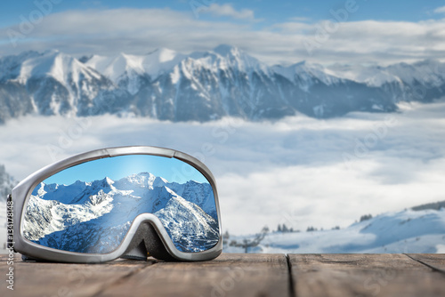 Ski goggles with reflection of mountains.