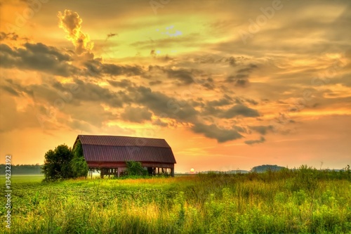 Wooden Barn Sunset. Rural sunset with an abandoned barn surrounded by farm fields.