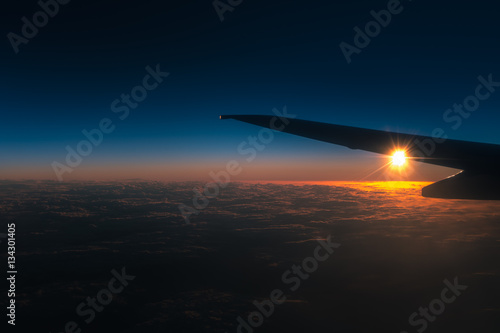 The airplane fly in a sky against the background of sunrise