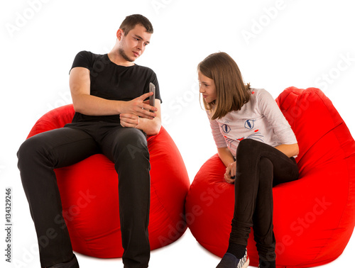 Young man and girl watching something on the phone while sitting
