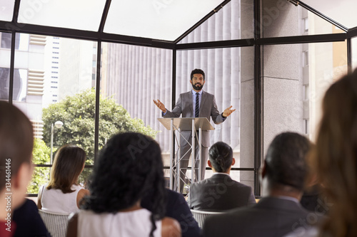 Hispanic man gesturing to audience at business seminar