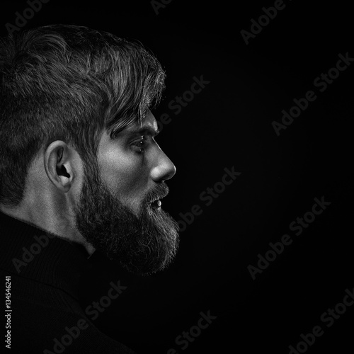 Black and white close up image of serious brutal bearded man on