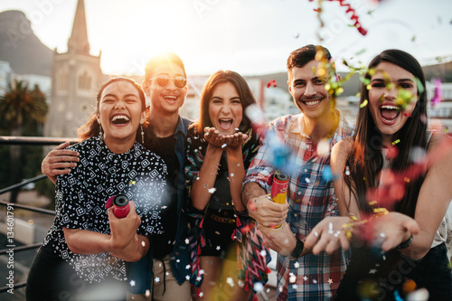 Friends enjoying party and throwing confetti