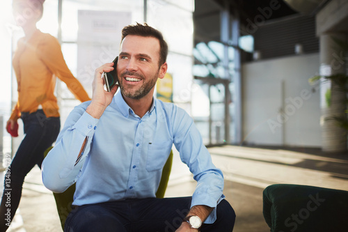 Handsome businessman talking on the phone during coffee break in