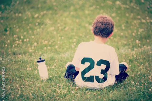 Boy sitting on sidelines with water bottle