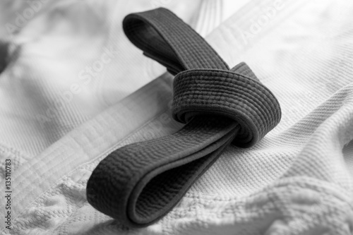 Black martial arts belt tied in a knot with white kimono in background