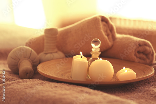 Spa set with candles, oil and towel on blurred background