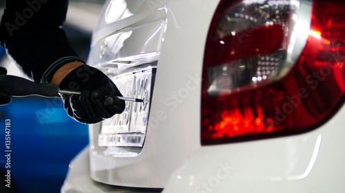 Mechanic in automobile service doing manual operations with car license plate number