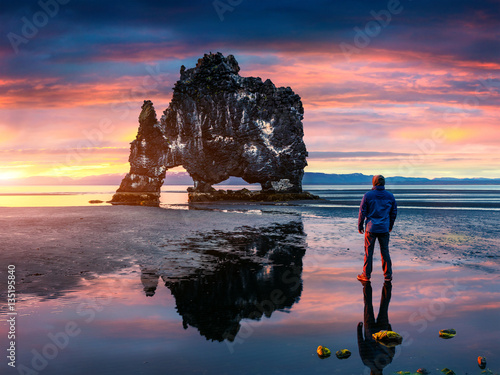 Man stands on the surface of water at fall of tide and and watch