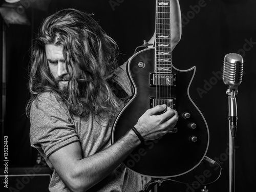 Attractive man playing electric guitar on stage.