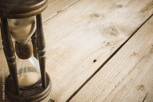 Old hourglass on wooden table