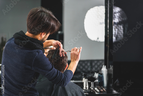 Professional stylist cutting male hair