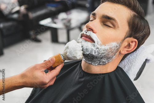 Skillful beautician preparing to shave stubble
