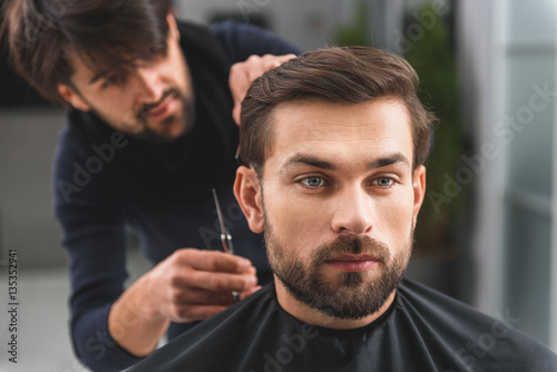Confident guy receiving service at hairdressers