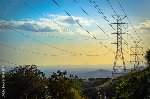 Sunset in the mountains over power lines with downtown Los Angeles skyline ithe the background.