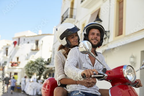 Young adult couple on a motor scooter in a street, Ibiza