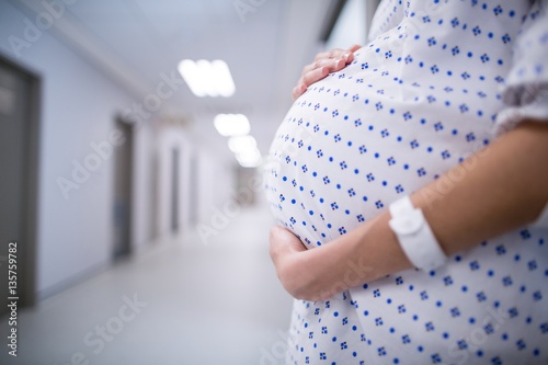 Mid section of pregnant woman standing in corridor