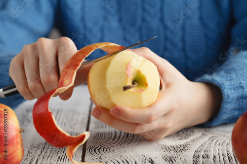 Girl peeling an apple on table