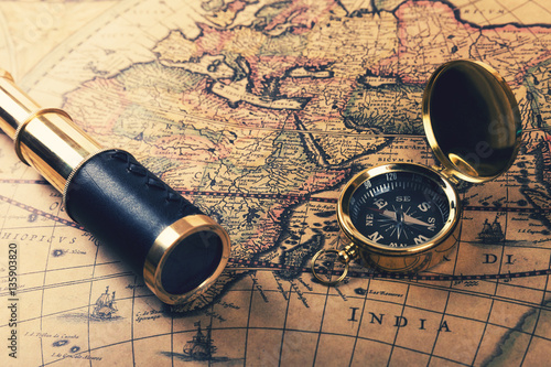 vintage compass and spyglass on old world map