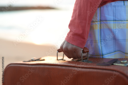 Back side view of person with suitcase on the beach outdoors background