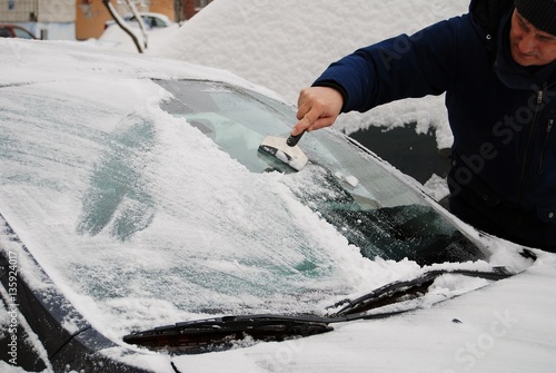 a man removes snow from car