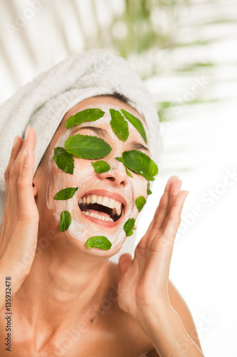 portrait d'une femme riant avec un masque de beauté sur le visage